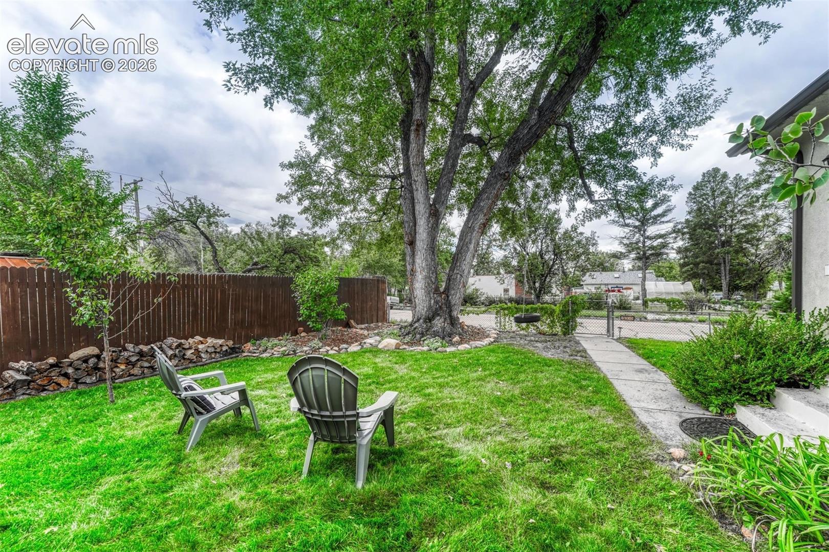 Fully fenced yard with a charming tire swing.