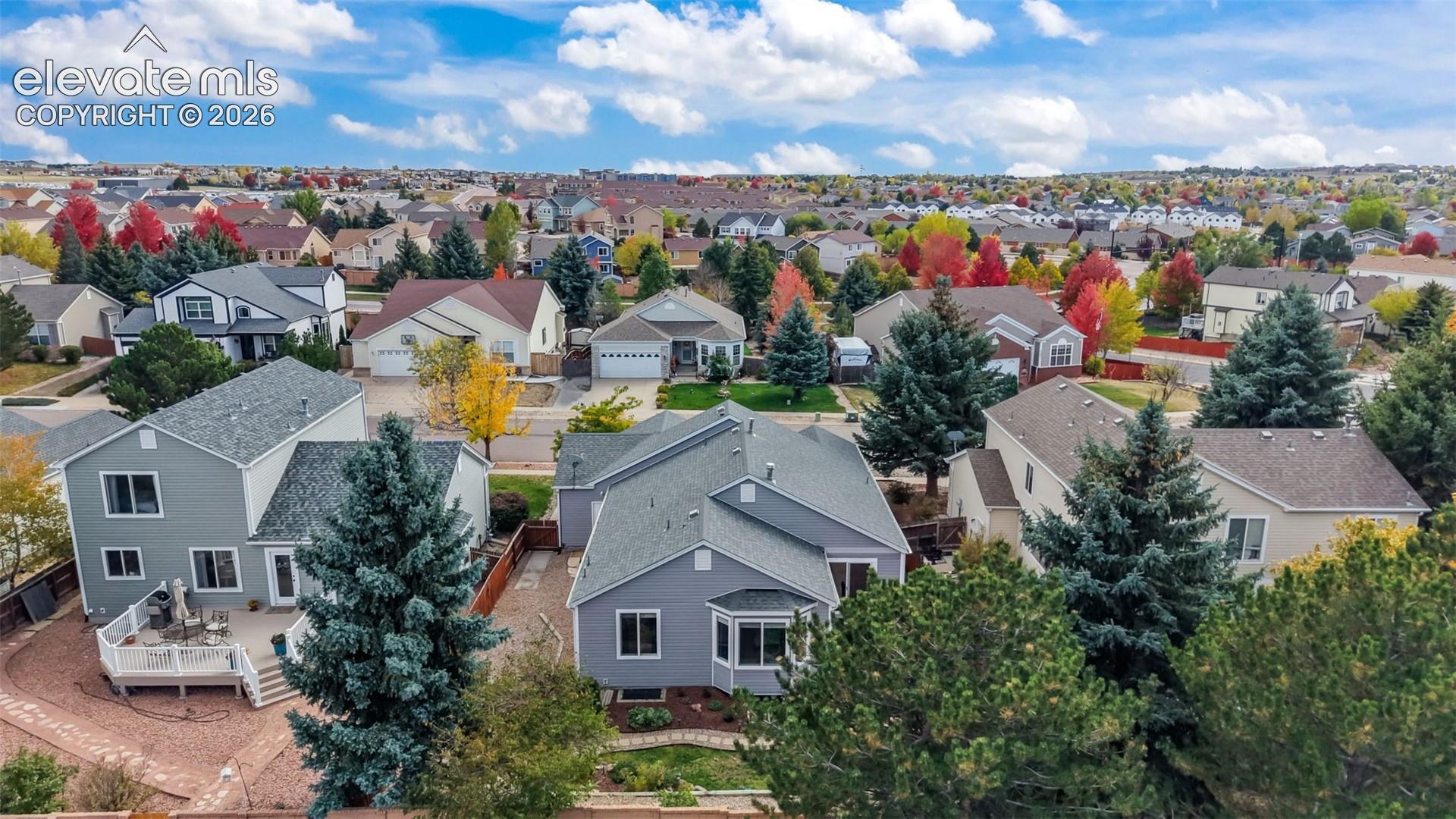 Aerial perspective featuring multi-story residential structures with composite shingle roofing, elevated rear decks, and established coniferous landscaping