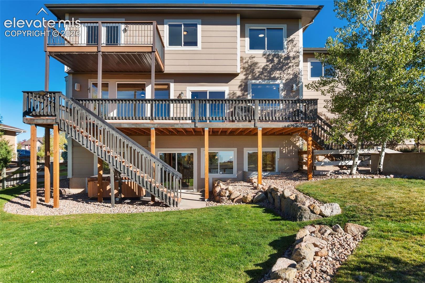 Two-story exterior featuring multi-level wood decks, metal railings, and exterior wood staircases