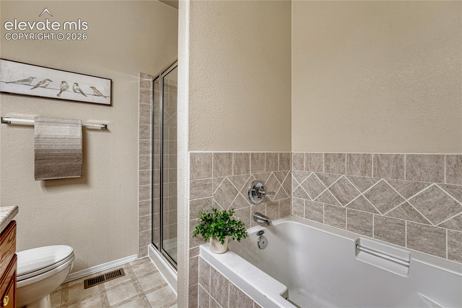 Unwind in the primary bath's deep soaker tub with custom tile surround or step into the separate walk-in shower
