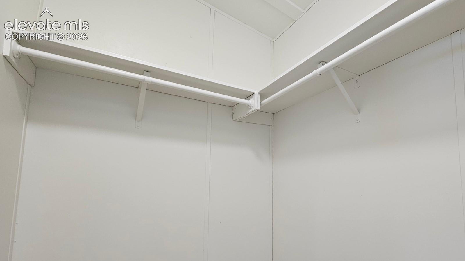Corner closet featuring dual-level integrated shelving and rod systems with wall-mounted supports