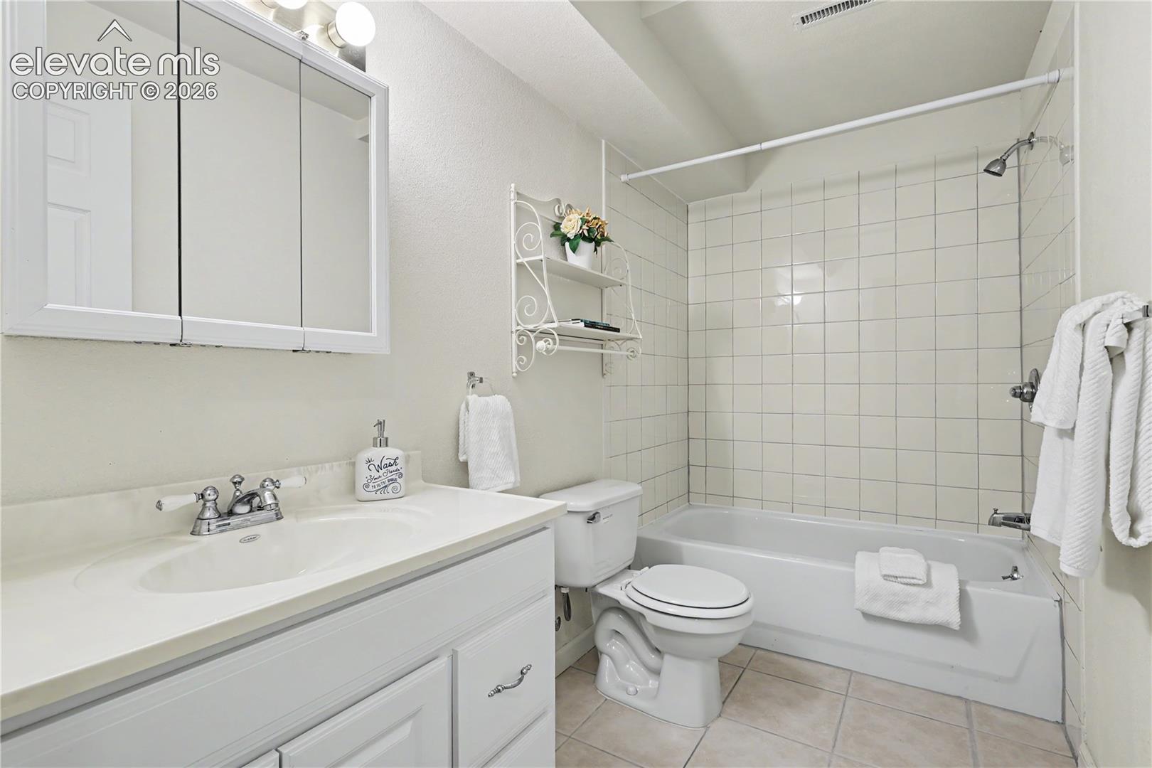 Bathroom featuring a white vanity with an integrated sink, chrome faucet, and a wall-mounted medicine cabinet with integrated lighting