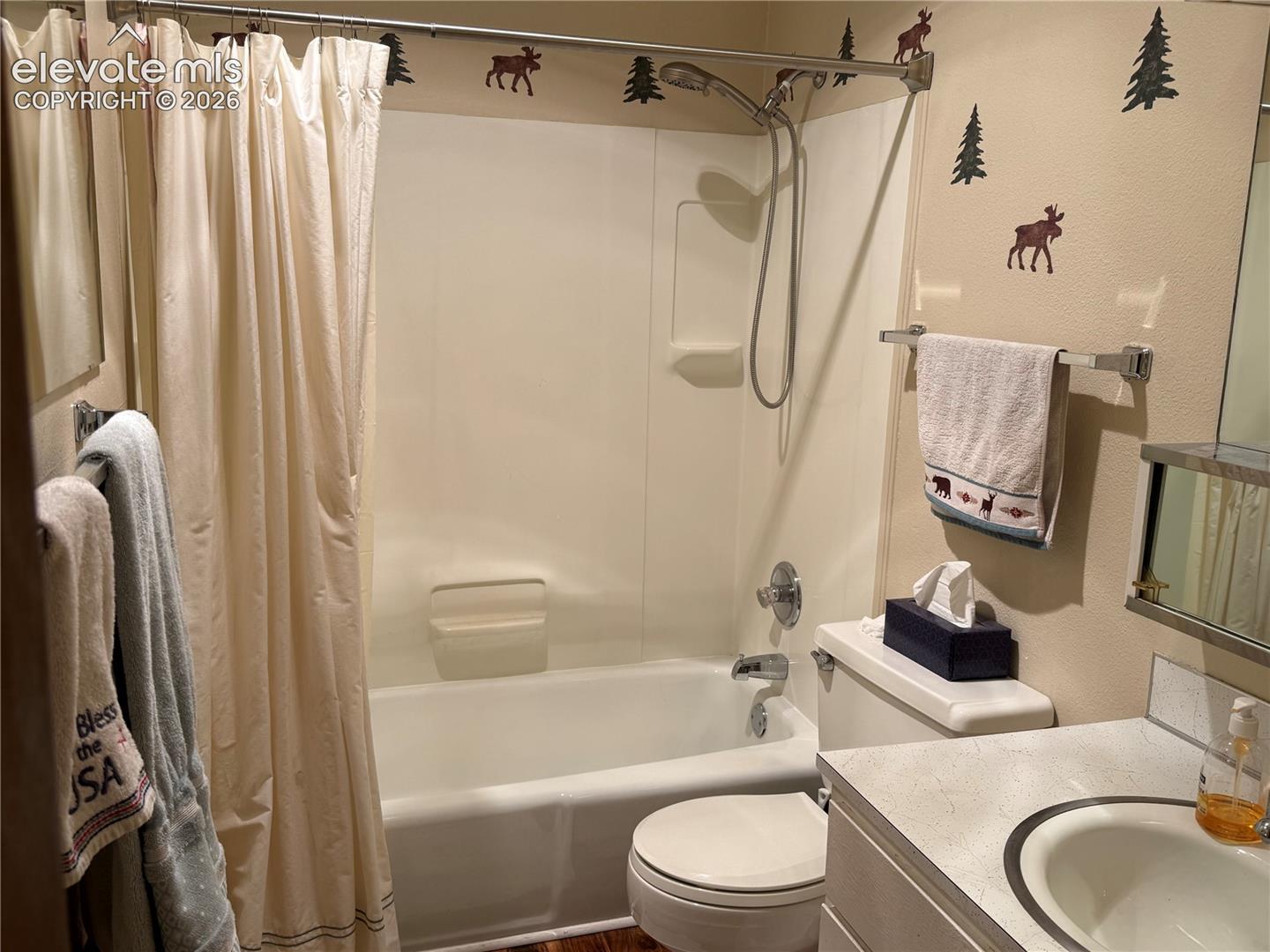 Bathroom featuring a molded composite tub and shower surround, handheld shower fixture, vanity with a solid-surface countertop, and an integrated basin