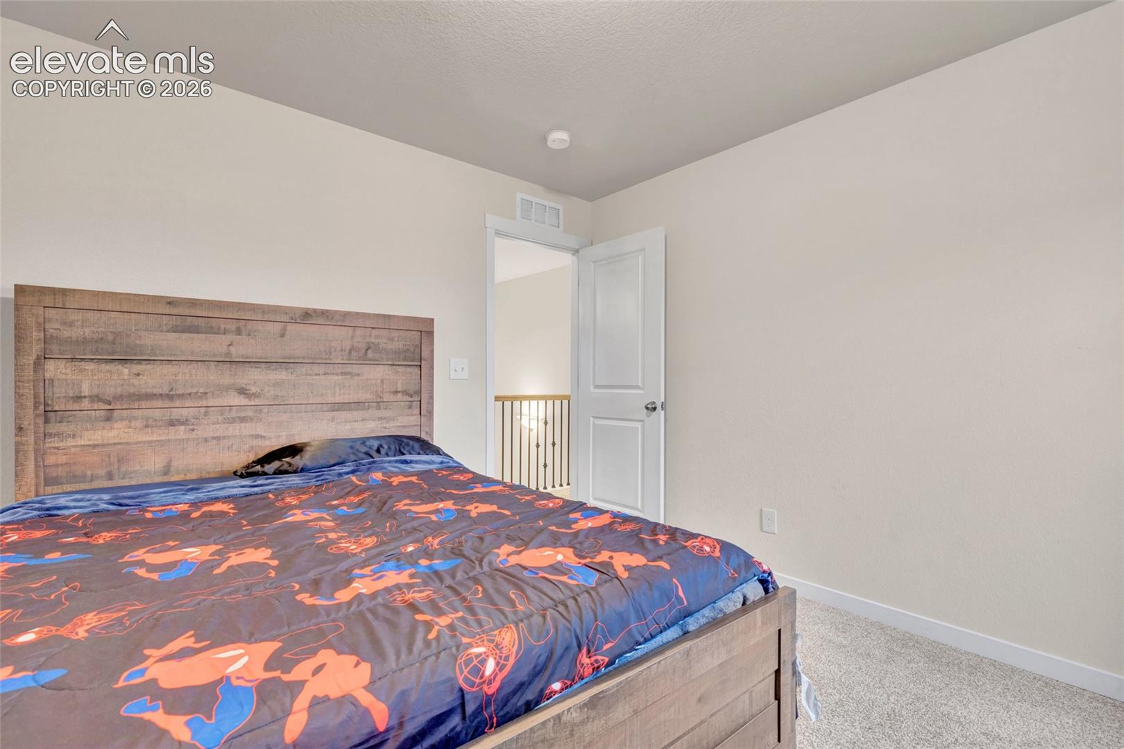 Neutral wall paint, light-colored carpeting, white door, overhead lighting, and white baseboards