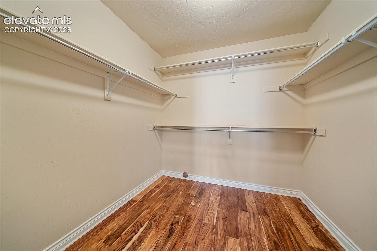 Walk-in storage space featuring wood-finish flooring and tiered metal shelving units