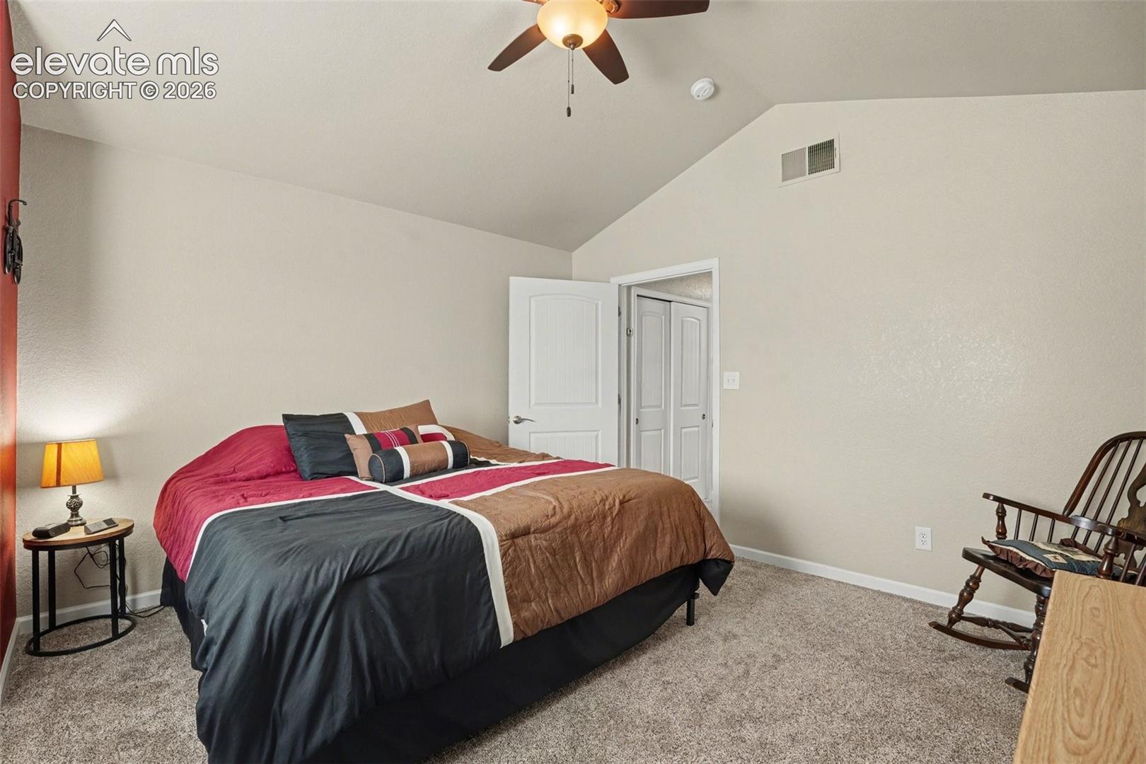 Vaulted ceiling featuring a central lighted ceiling fan, neutral wall tones, and carpeted flooring