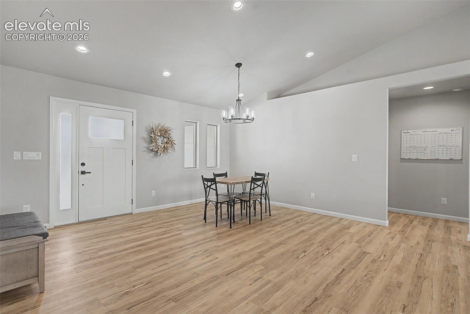 Open concept living space featuring wood-finish flooring, recessed lighting, and a vaulted ceiling
