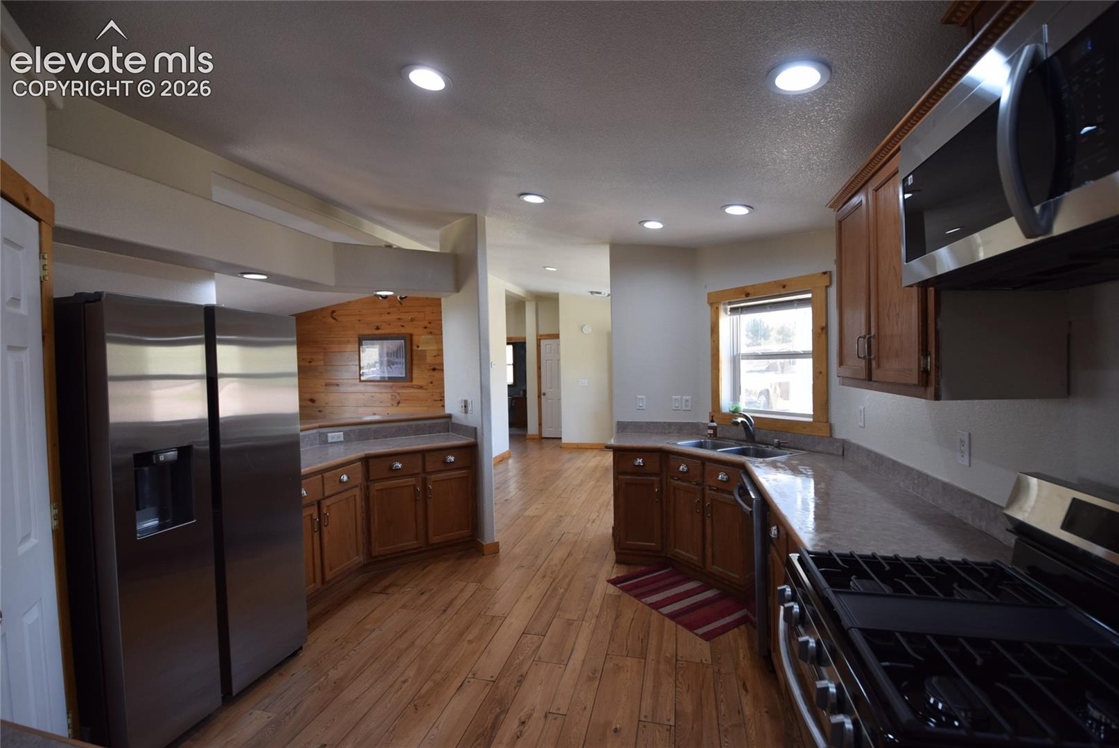 Kitchen featuring wood-finish flooring, recessed lighting, wood cabinetry, stone-finish countertops, and stainless-steel appliances