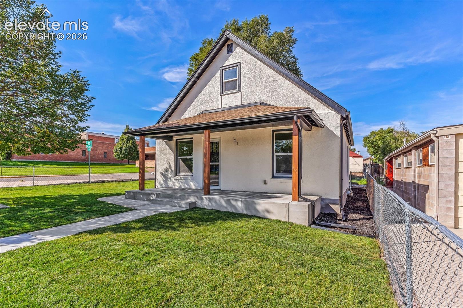 Stucco exterior featuring a covered front porch with wood-finish support posts, a concrete foundation, and a shingled roof