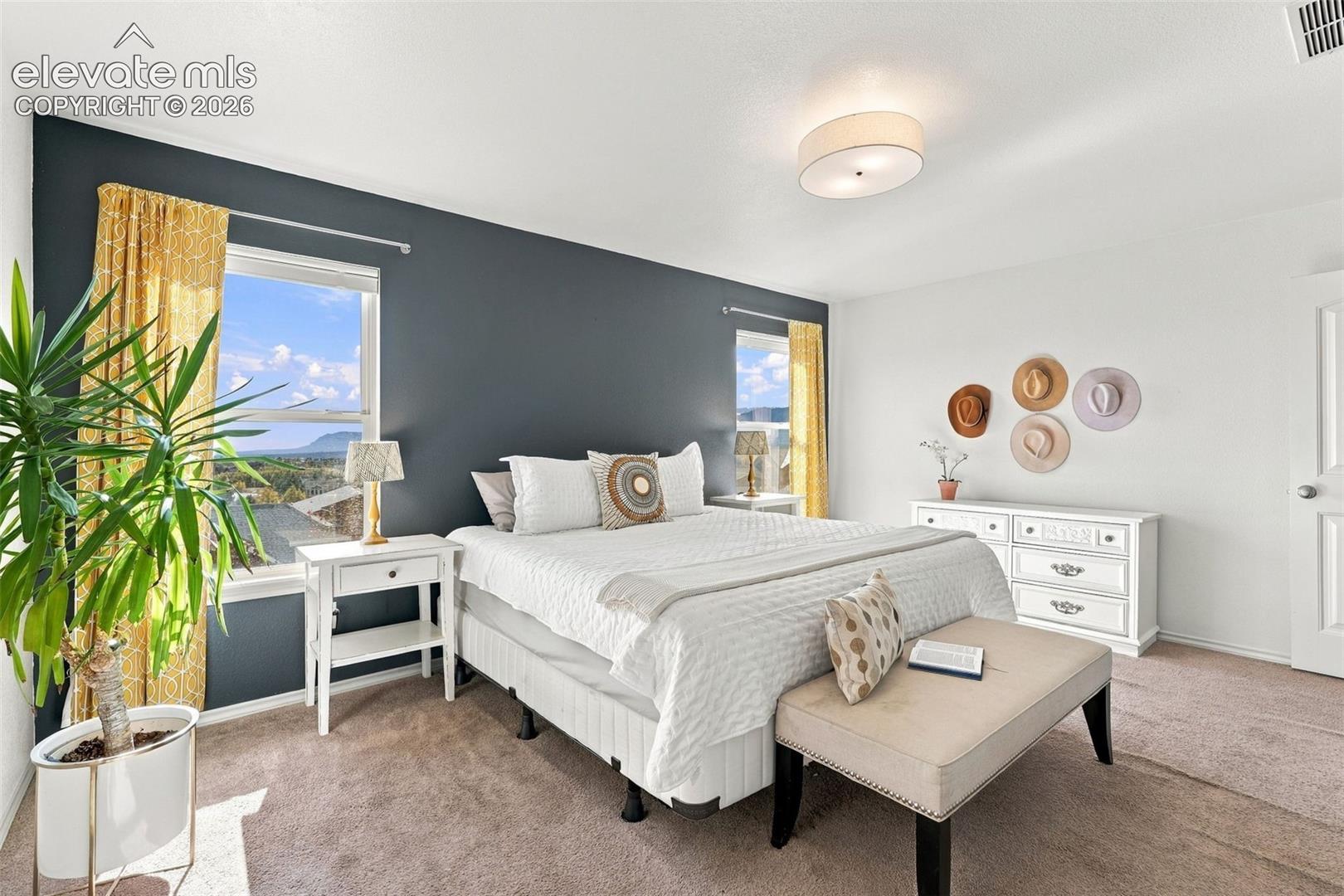 Neutral-toned carpeted flooring, charcoal accent wall, two large windows, and a central drum-style ceiling light fixture