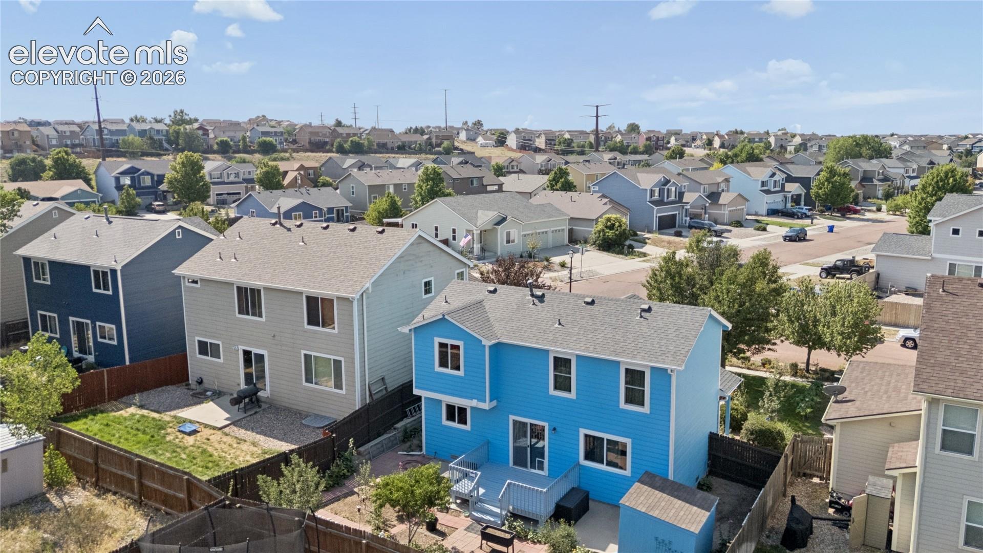 Rear exterior featuring a blue siding finish, an elevated wood deck, a sliding glass door, multiple windows, and a fenced backyard