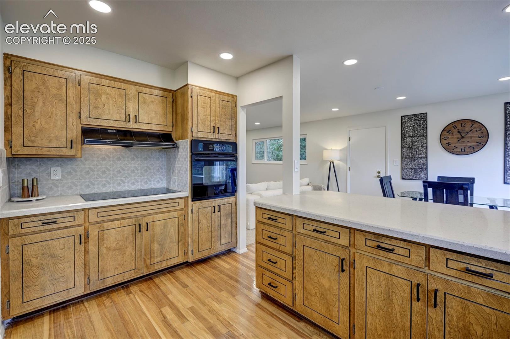 Kitchen featuring wood cabinetry, recessed lighting, built-in double wall oven, patterned tile backsplash, and stone-surface countertops