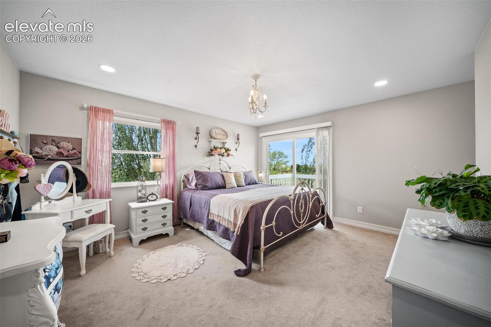 Spacious room with plush carpeting, recessed lighting, and a decorative chandelier