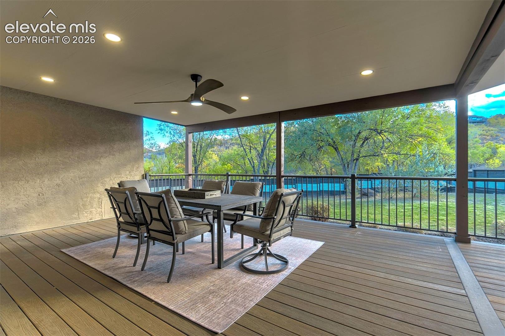 Covered deck featuring wood-finish decking, recessed ceiling lighting, a ceiling fan, and metal perimeter railing