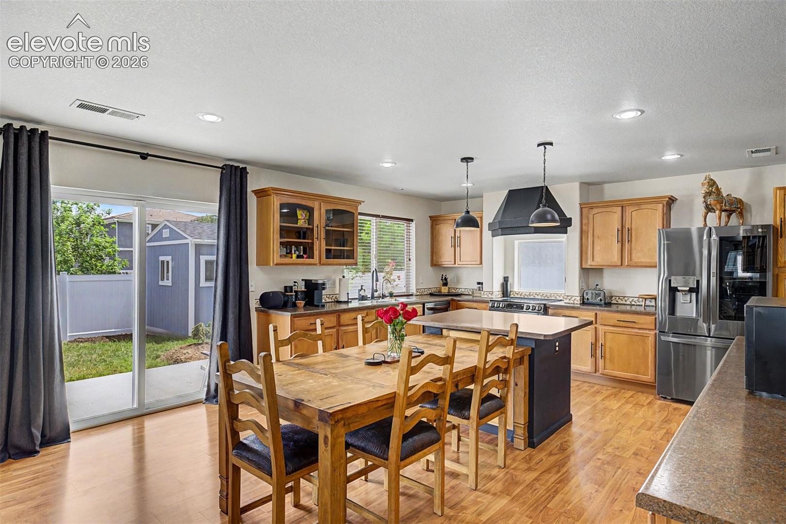 The kitchen's dining area is bathed in natural light from a large slider that opens directly to the backyard patio — making indoor-outdoor living effortlessly easy.