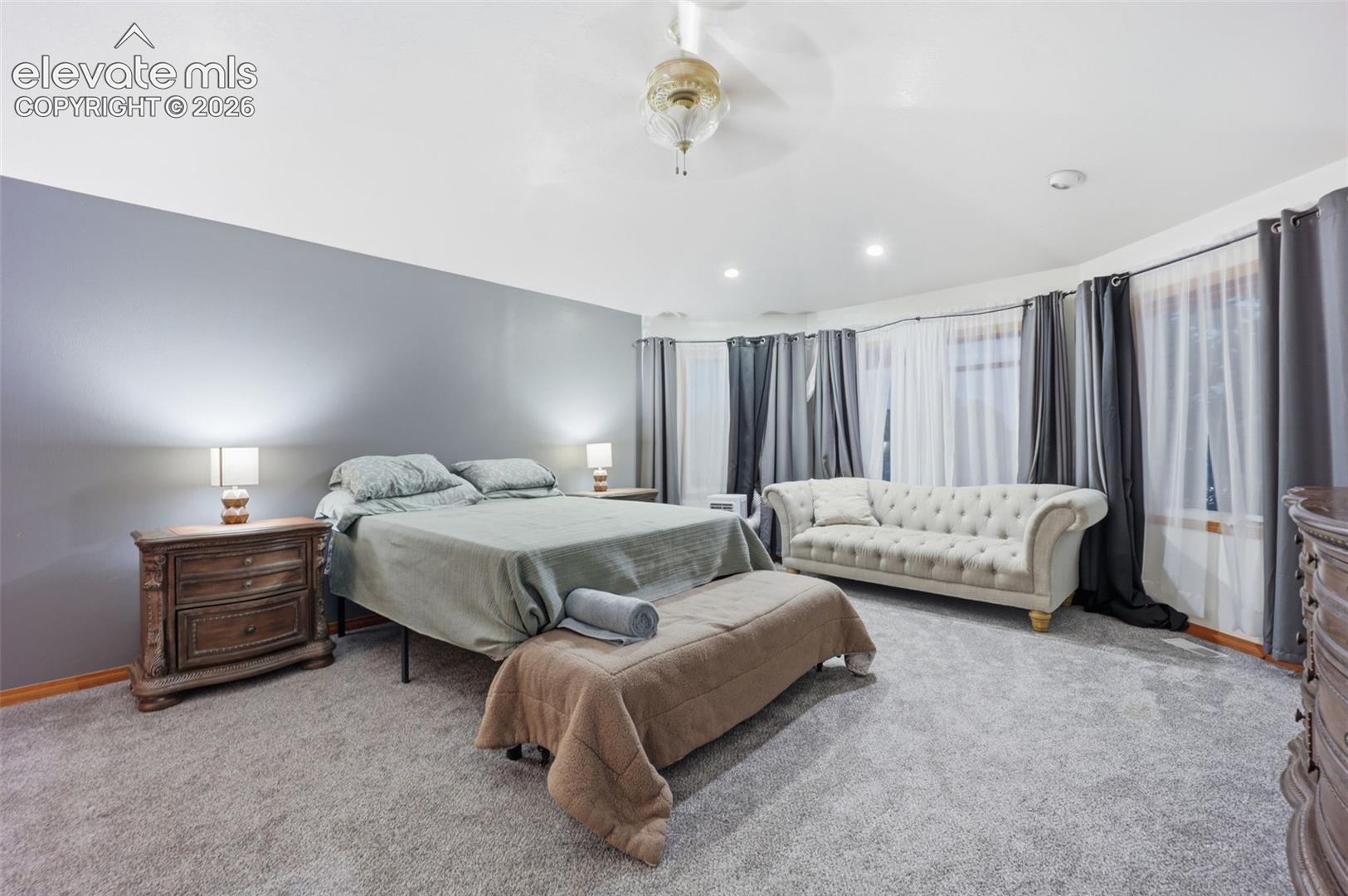 Recessed lighting, ceiling-mounted light fixture, light gray carpeting, floor-to-ceiling windows, and wood-finish trim