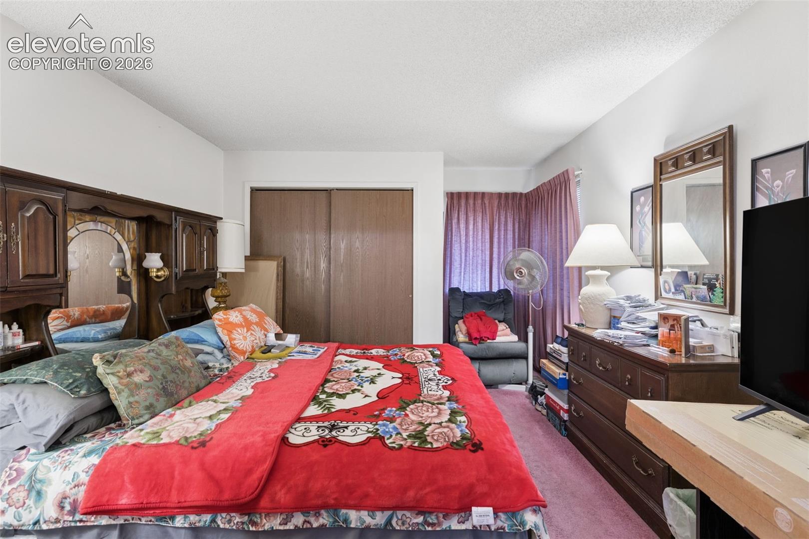 Bedroom featuring built-in wood-finish cabinetry, a mirror with wood-finish framing, and a closet with sliding doors