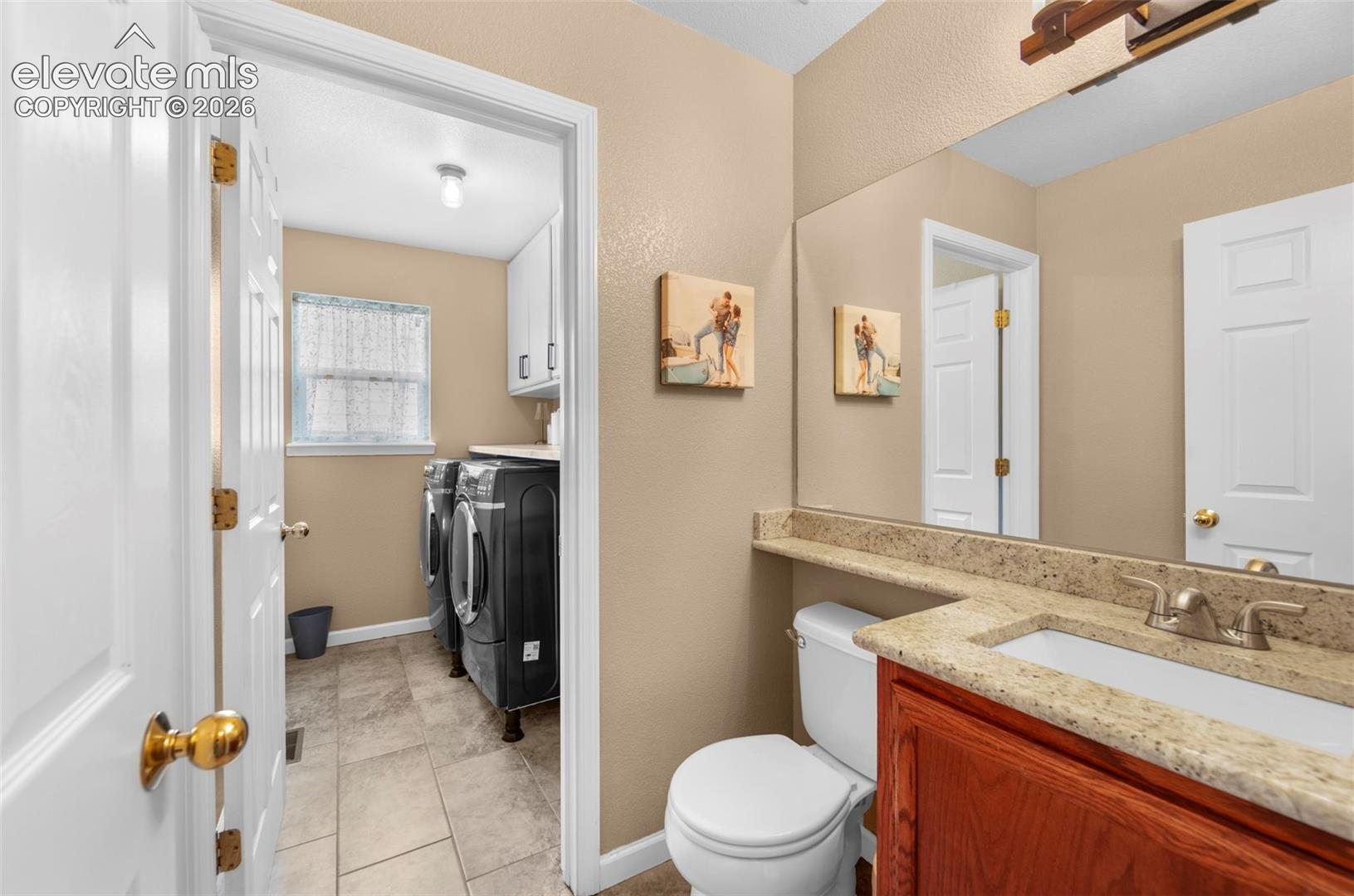 Bathroom vanity featuring a granite-style countertop, undermount sink, and wood-finish cabinetry