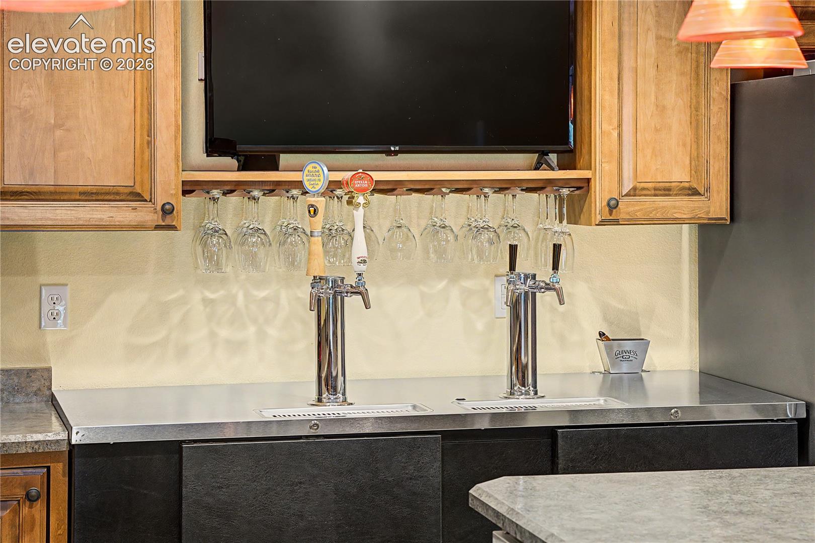 Dual beer taps and built-in glass storage show this bar was designed with hosting top of mind.