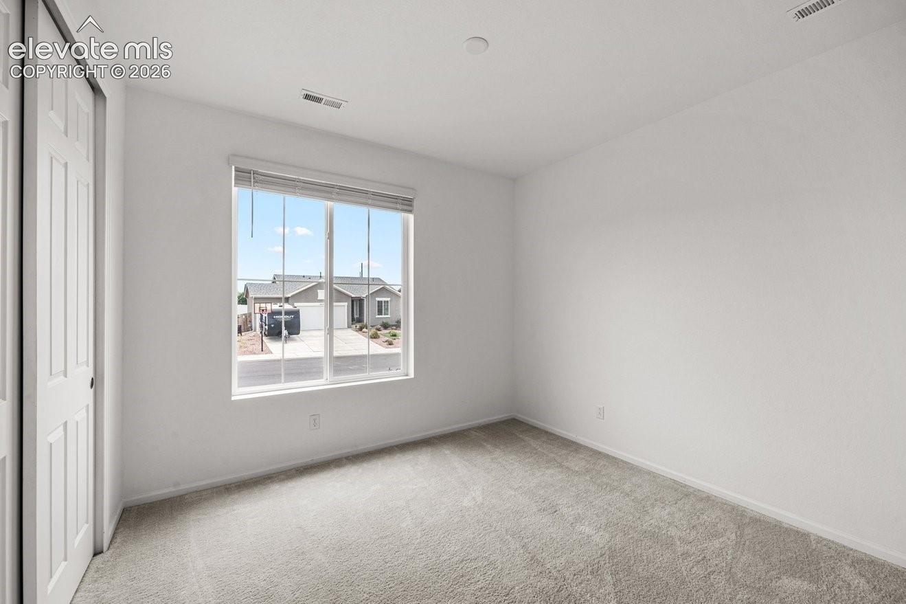 Neutral-toned carpeting, white walls, and a large window with blinds
