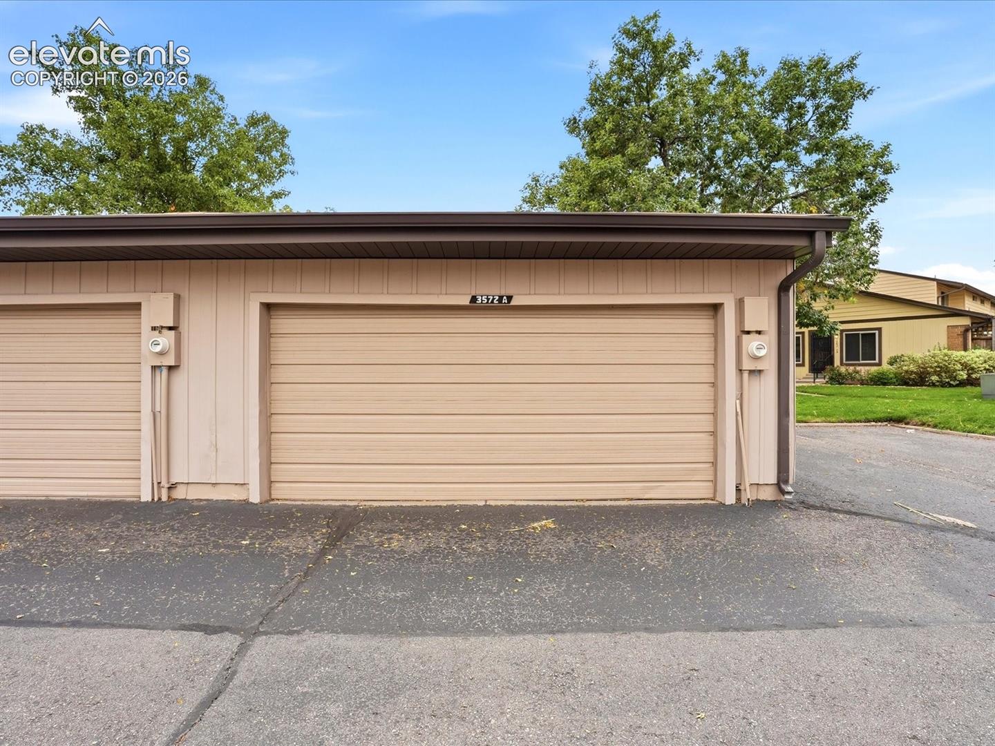 Detached garage featuring vertical siding, horizontal panel doors, and an asphalt approach