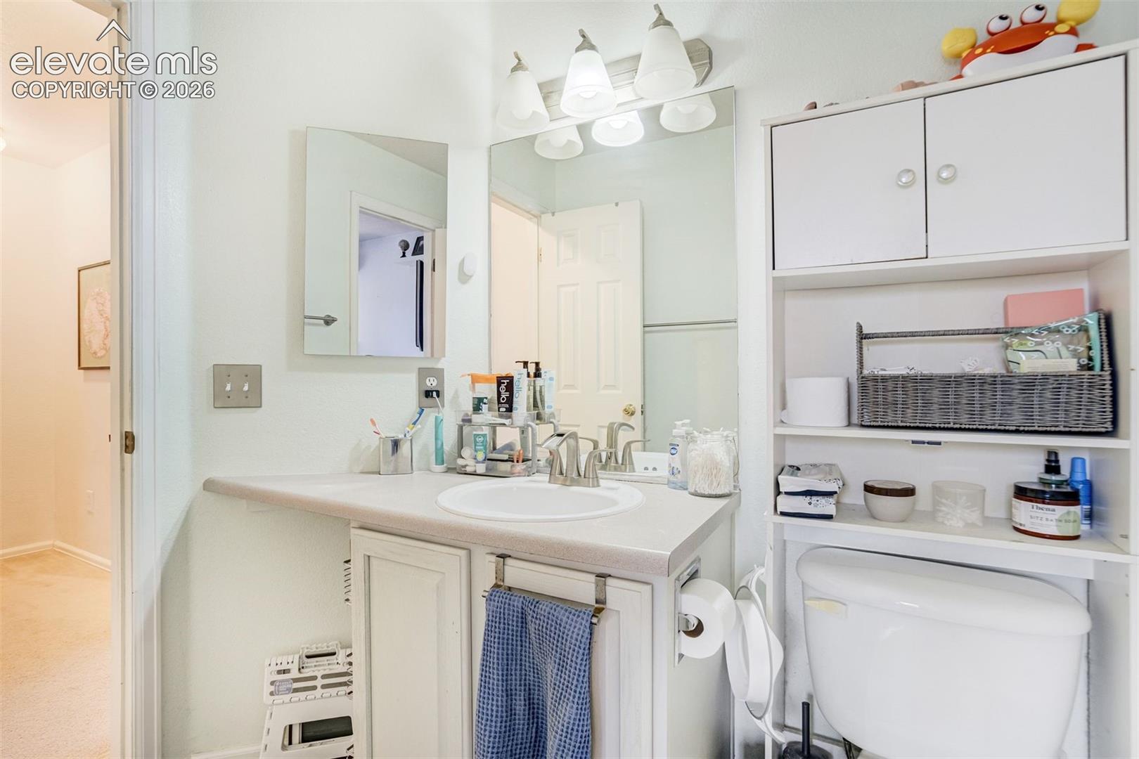 White vanity with an integrated sink and brushed nickel faucet, illuminated by a three-light fixture