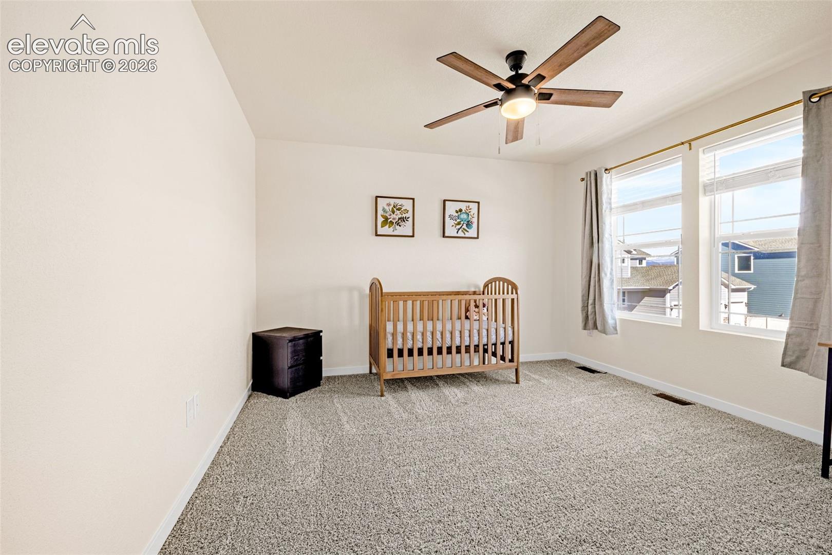 Wall-to-wall carpeting, multiple windows providing ample ambient light, and a ceiling fan with light fixture