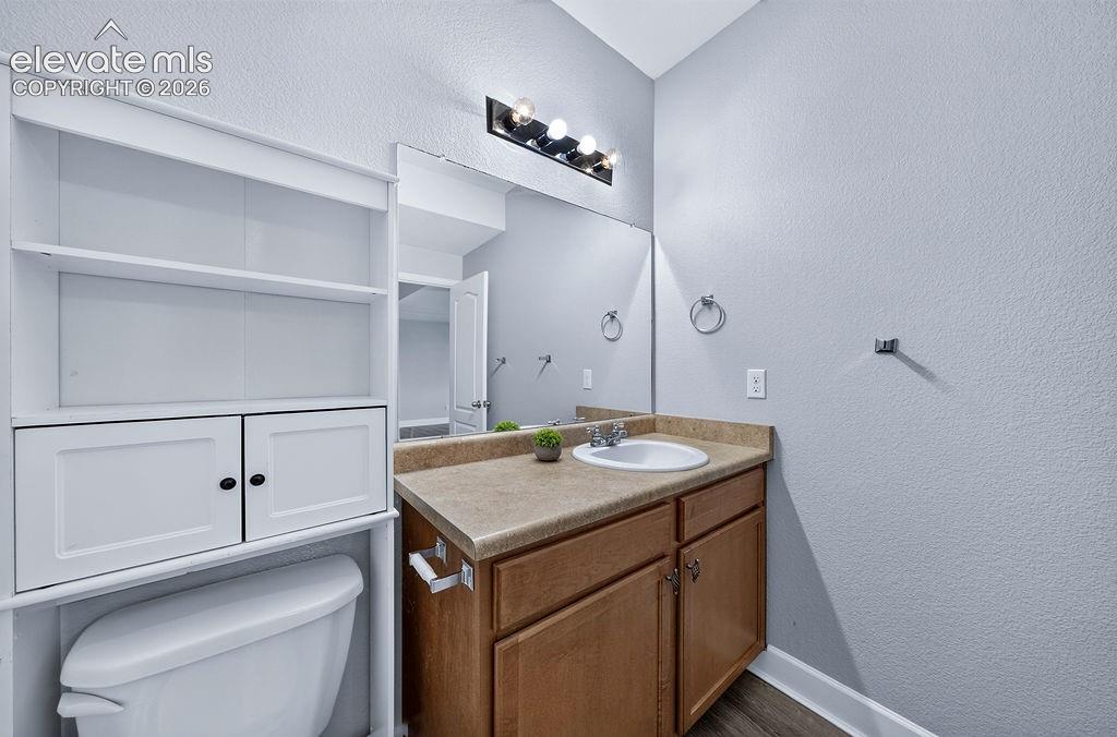 Vanity with an integrated sink and laminate countertop, wood-finish flooring, and a built-in white storage cabinet