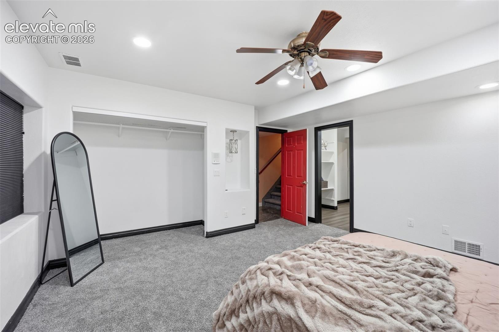 Plush gray carpeting, white walls, and a ceiling fan with integrated lighting