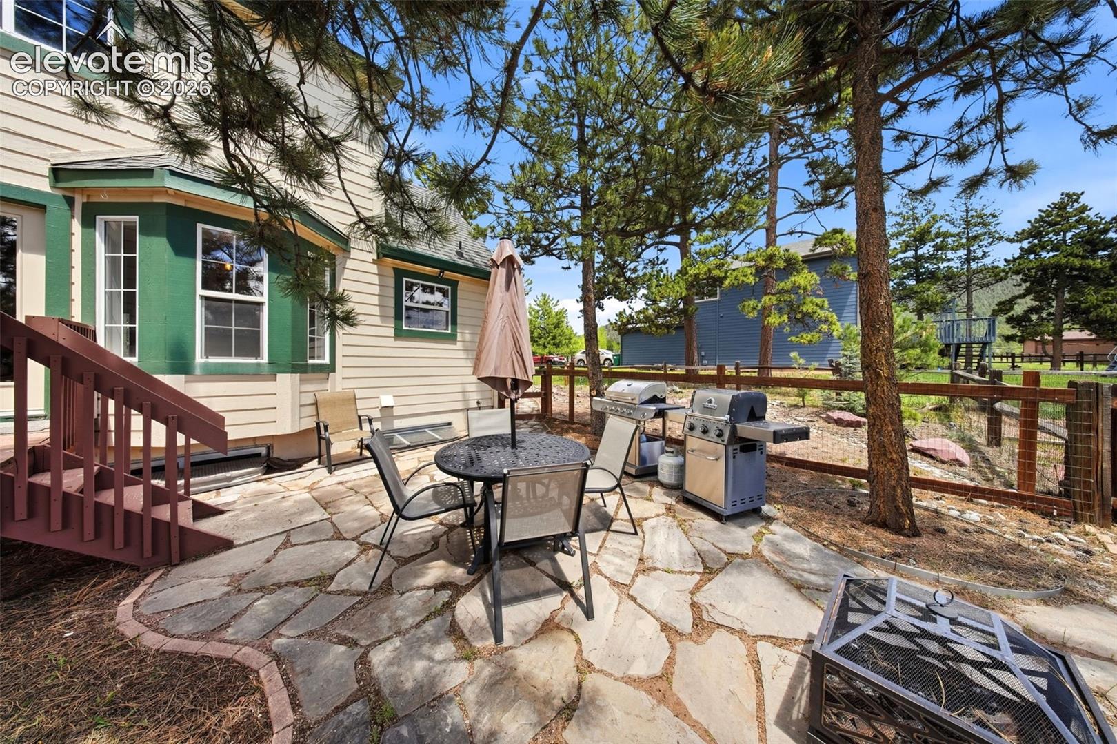 Flagstone patio featuring a bay window, wood-finish siding, and mature trees