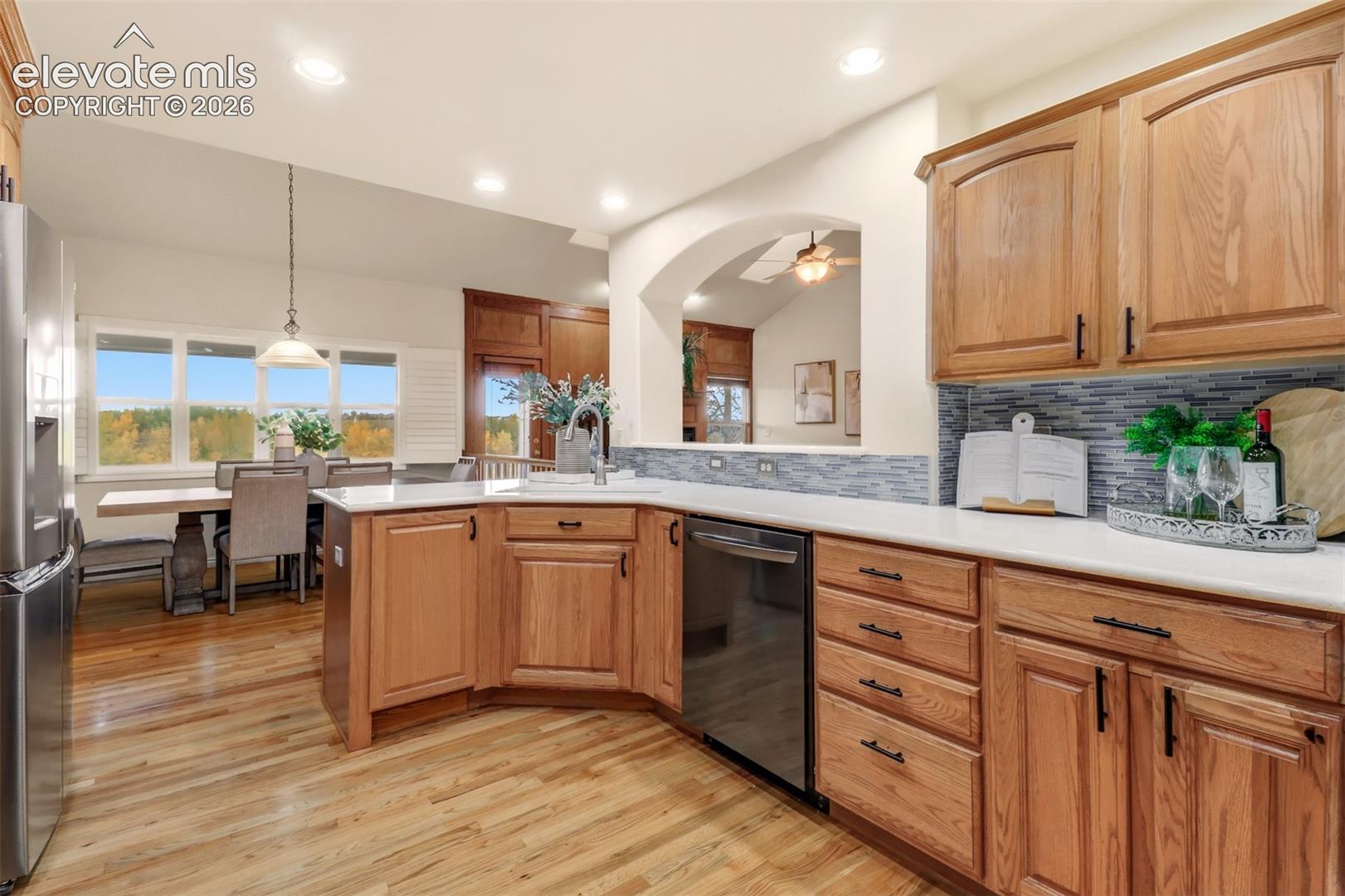 Kitchen featuring solid wood cabinetry, white countertops, a tiled backsplash, recessed lighting, and wood-finish flooring