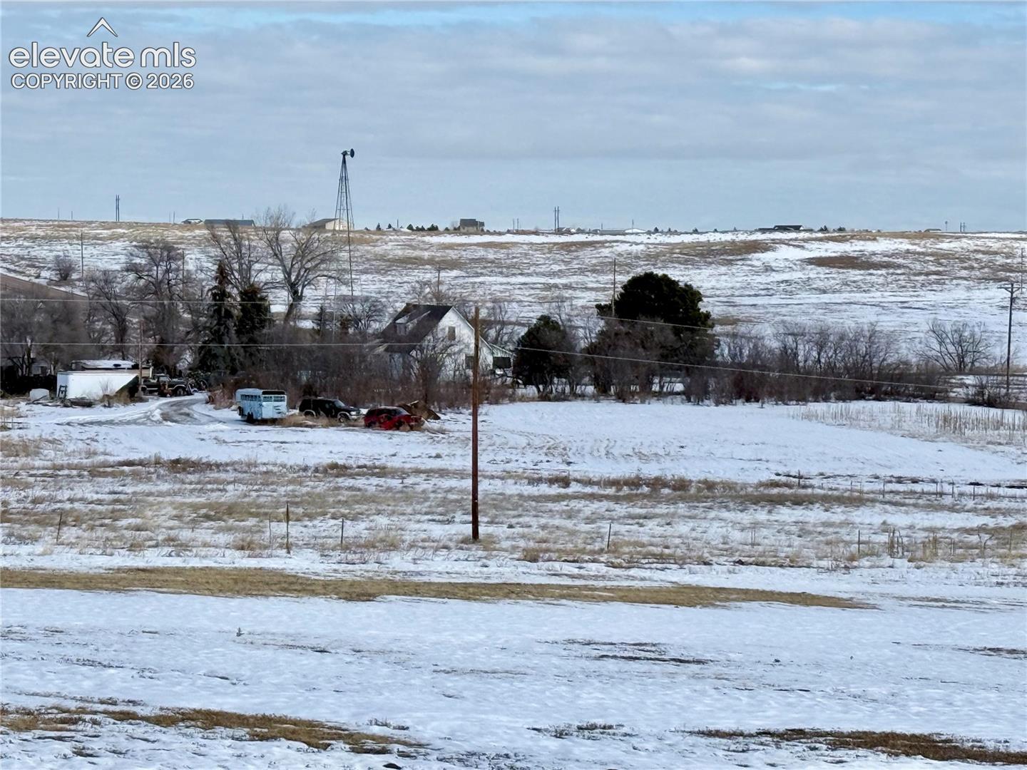 Expansive acreage featuring mature trees, a functional windmill, and open terrain
