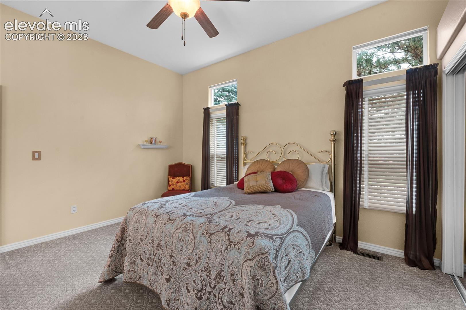 Vaulted ceiling, ceiling fan with light fixture, wall-to-wall carpeting, and transom windows