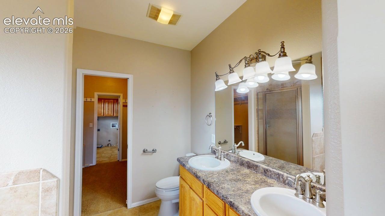Dual vanity with integrated sinks, brushed nickel fixtures, and a multi-bulb light fixture above