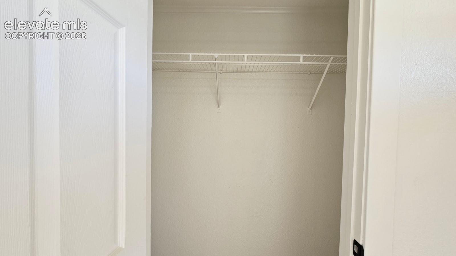 Storage space featuring a white swing door and a built-in wire shelving system