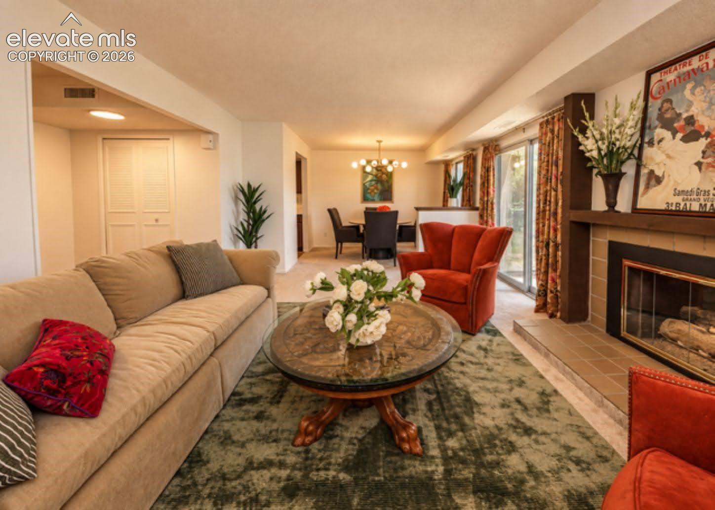 Fireplace with tile hearth and wood surround, glass sliding doors, and multi-light chandelier