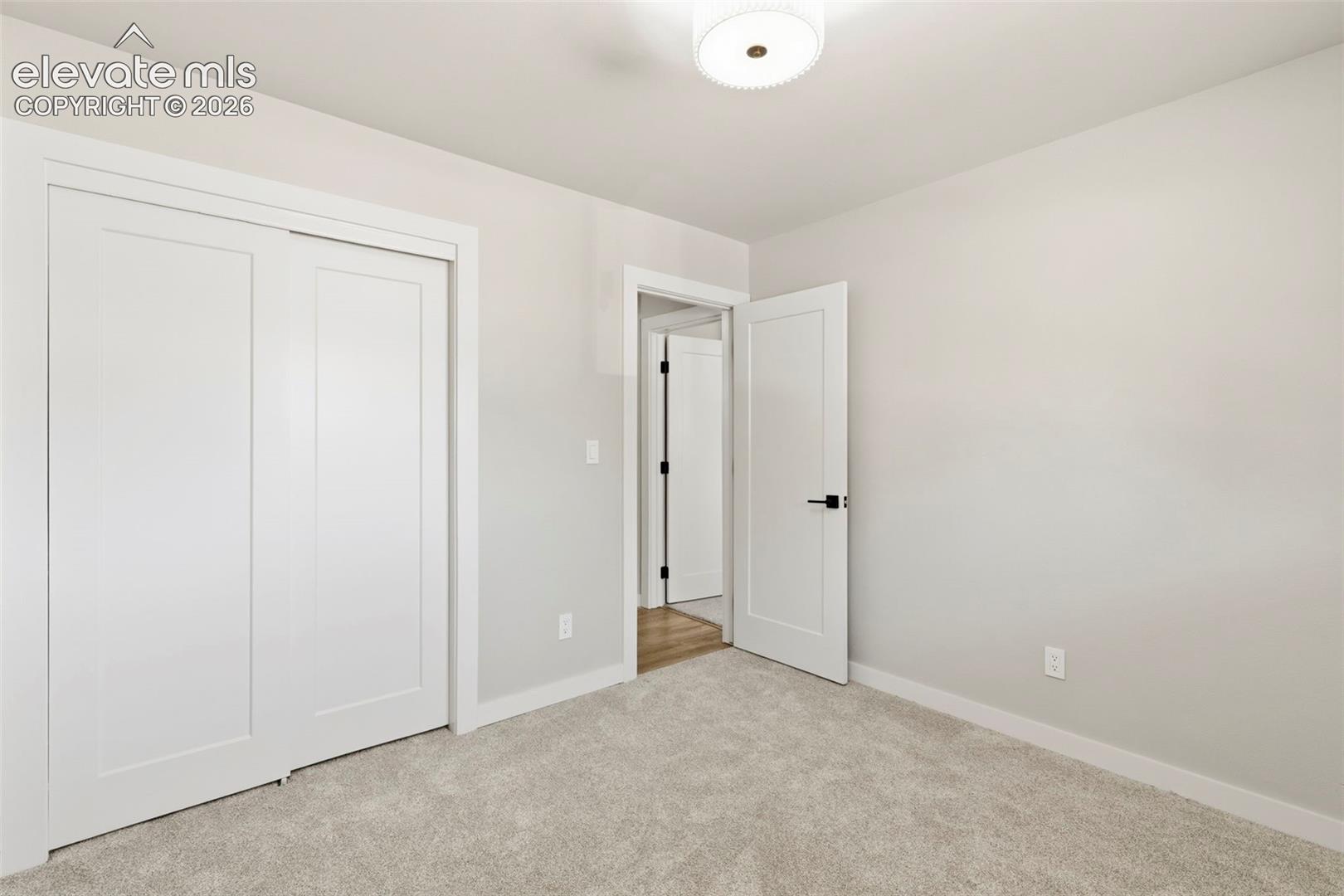 Carpeted room featuring a white ceiling, light gray walls, white baseboards, and a semi-flush mount ceiling light