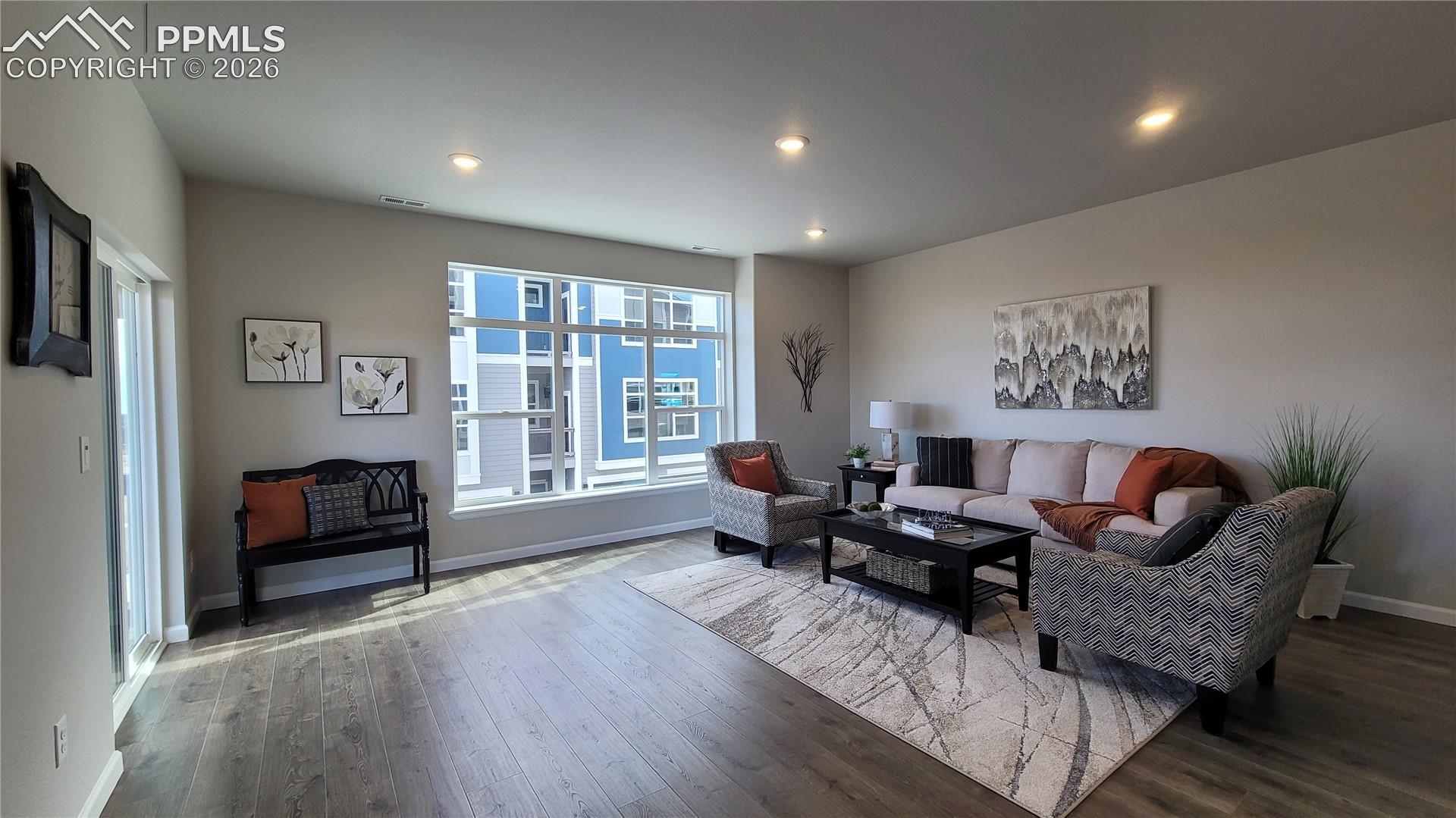 Living room with LVP flooring, abundance of natural light, LED lighting, and walk out to private deck! 