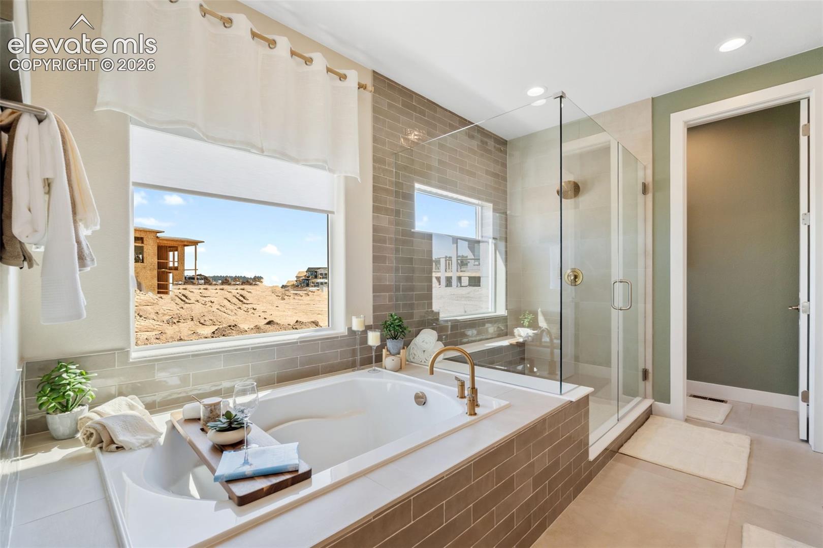 Soaking tub with a brass-finish faucet, walk-in glass-enclosed shower, and subway-style wall tile