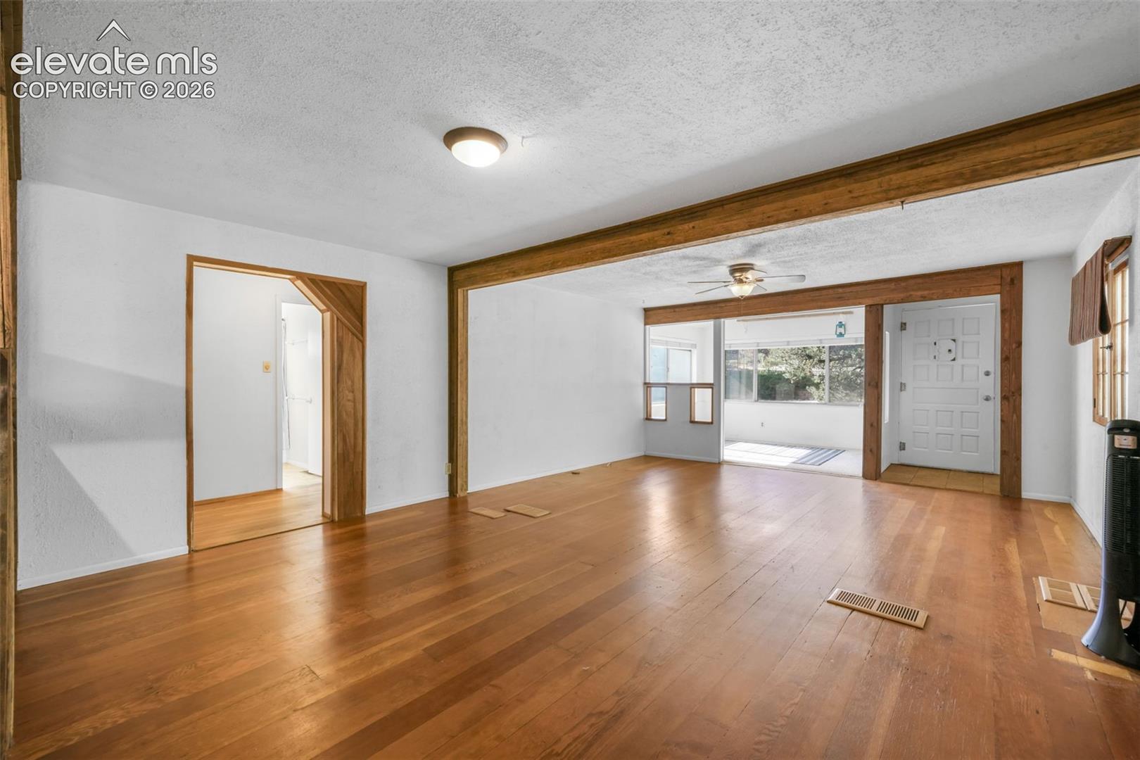 Hardwood flooring, exposed wood beams, ceiling fan, white paneled door, and recessed lighting