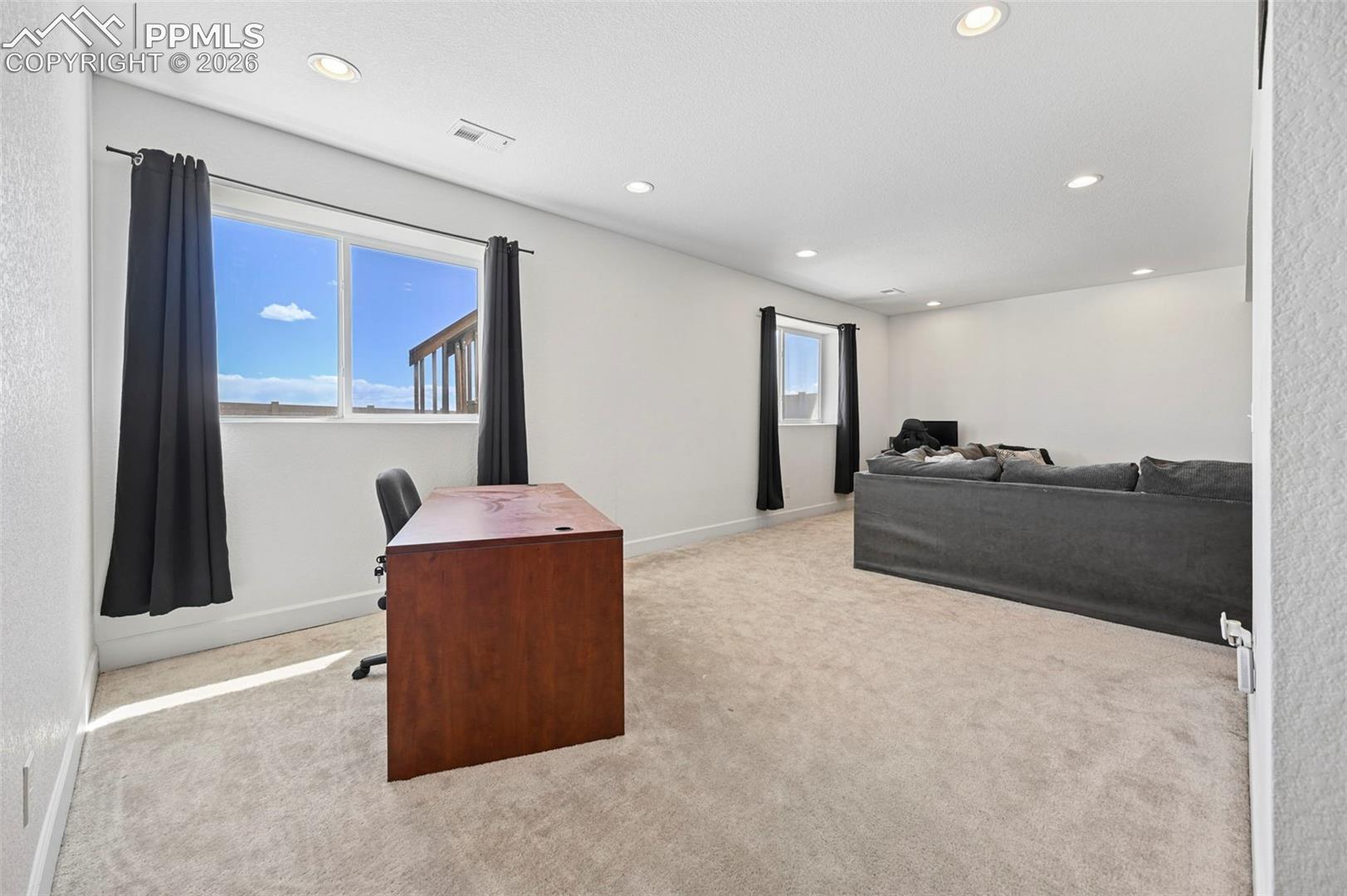 Spacious room featuring light-colored carpeting and recessed lighting