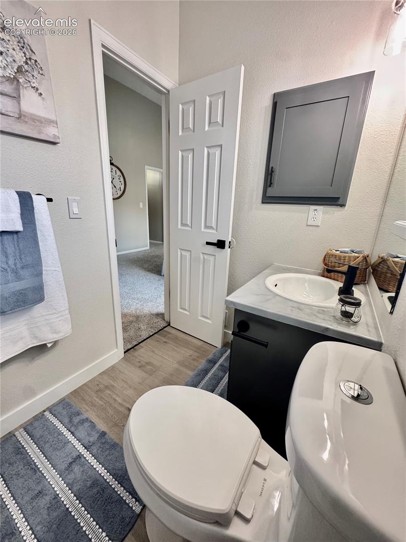 Vanity featuring a stone-surface countertop with an integrated basin, matte black faucet, wood-finish cabinetry, and a wall-mounted medicine cabinet