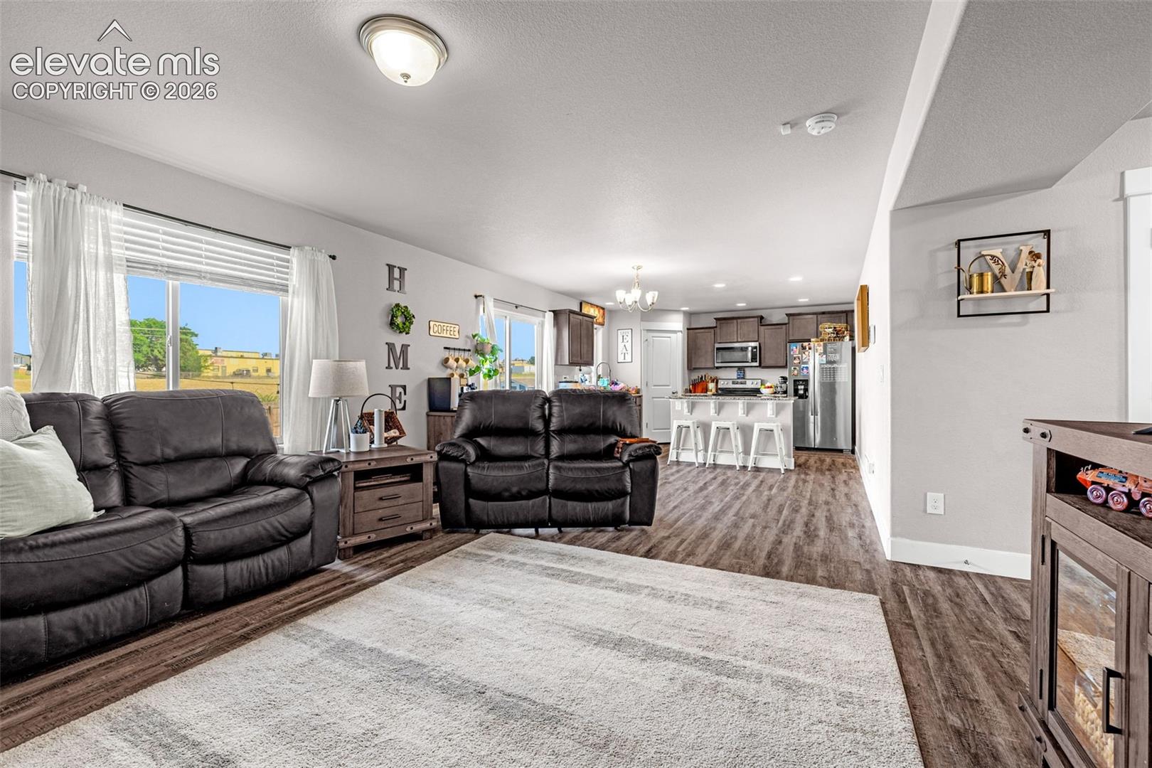 Open-concept living area featuring wood-finish flooring, recessed lighting, and large windows providing ample natural light