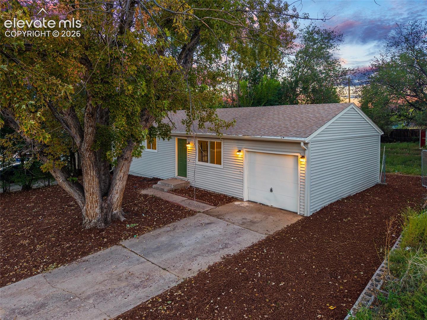 Single-story residence featuring light gray siding, a prominent attached single-car garage, and a concrete driveway