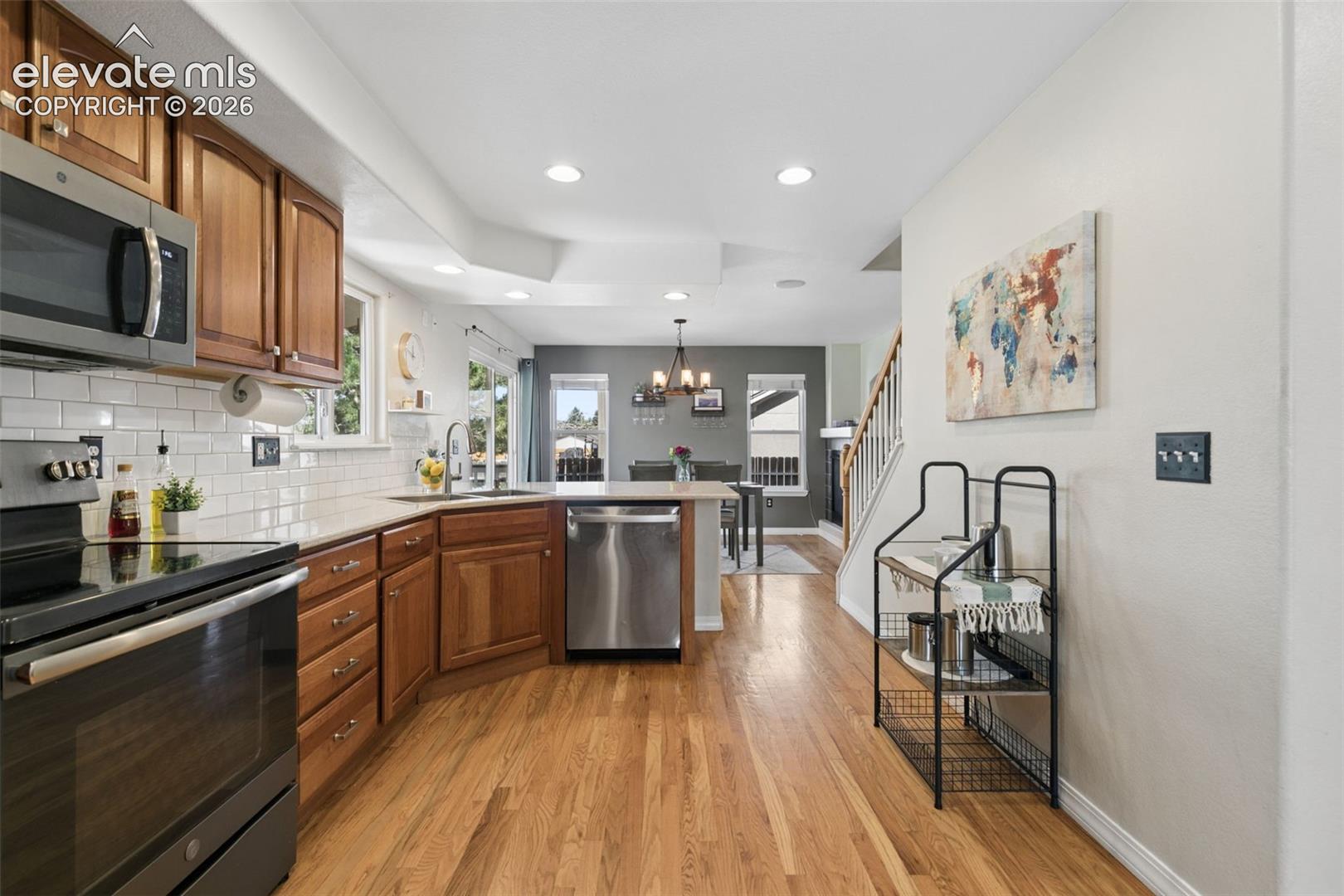 Kitchen featuring wood-finish flooring, stainless steel appliances, and white subway tile backsplash
