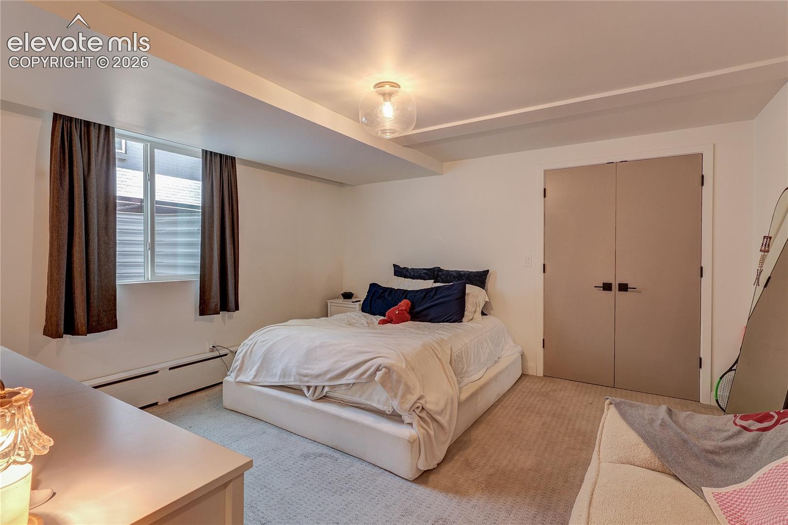 Window with dark curtains, flush-mount ceiling light fixture, recessed lighting, double closet doors with dark hardware, and carpet flooring