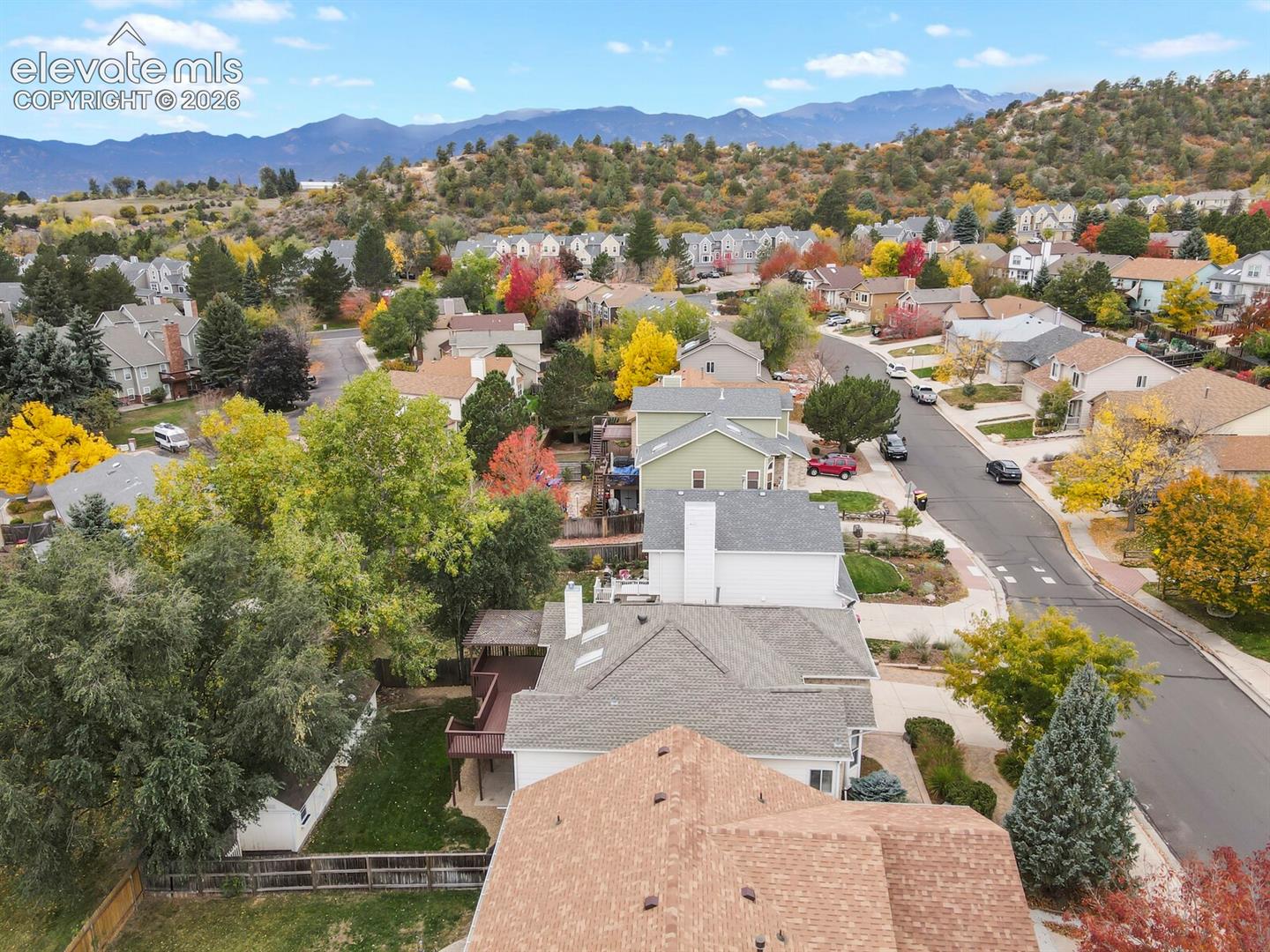 Aerial perspective featuring mountain topography, mature tree canopy, asphalt street infrastructure, residential siding, and composite roofing