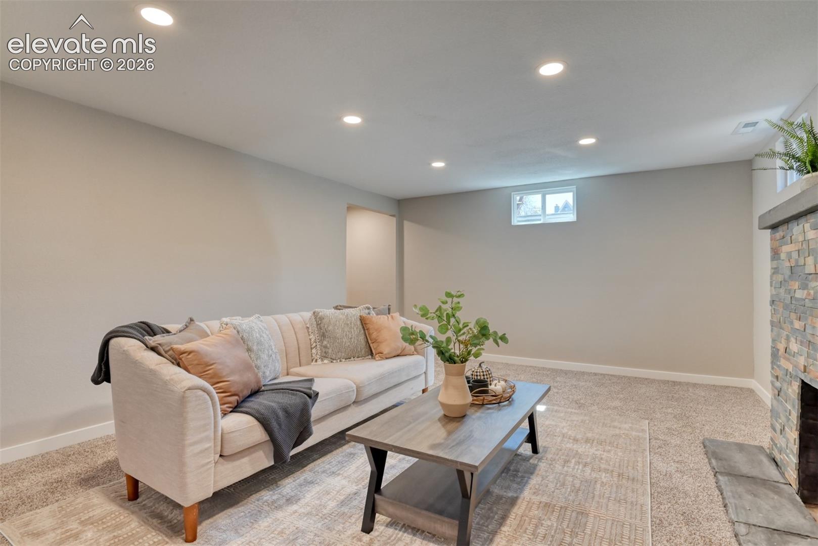 Recessed lighting, light-colored walls, window, stone-clad fireplace, carpeted flooring
