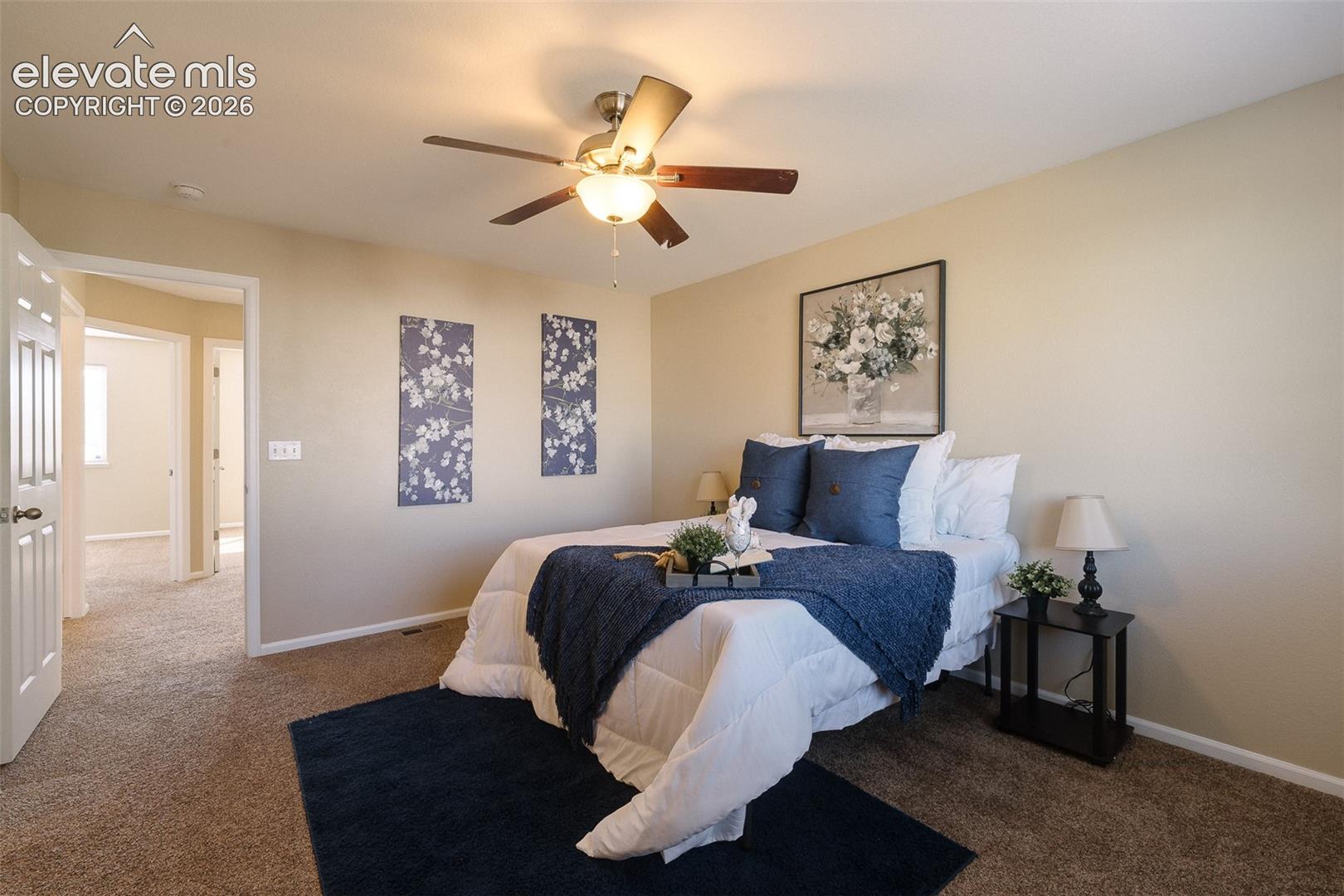 Neutral-toned wall paint, neutral carpeting, and a central ceiling fan with an integrated light fixture
