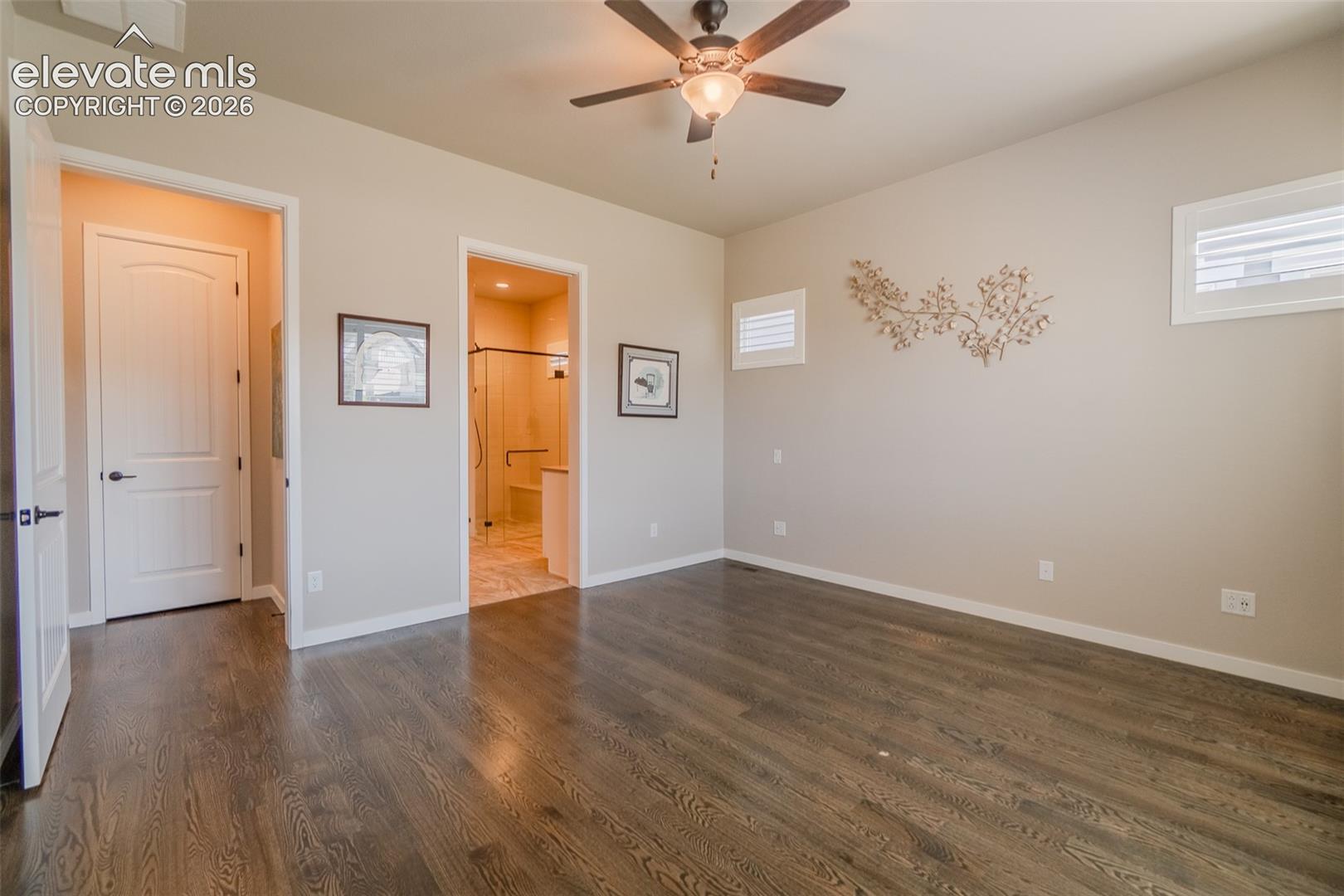 Bedroom featuring wood-finish flooring, a ceiling fan with integrated lighting, and multiple windows with plantation shutters